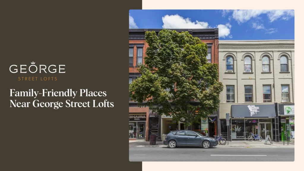 A sunny street view shows historic brick buildings with storefronts on the ground level, featuring a large, mature tree obscuring the second floor of the central building. A dark gray car is parked on the street. The image is used alongside the text "Family-Friendly Places Near George Street Lofts."
