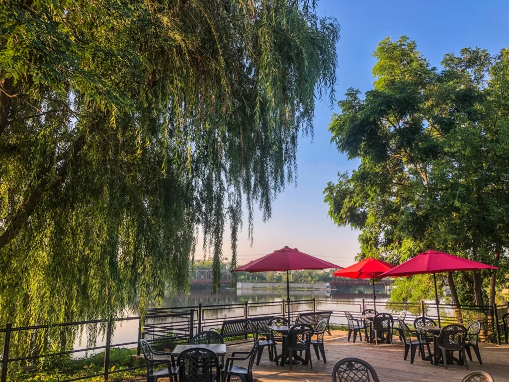 Outdoor patio seating at The Silver Bean Café by the river with red umbrellas